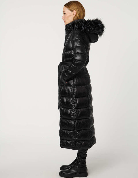 Person wearing a long black puffer coat with fur hood on a white background