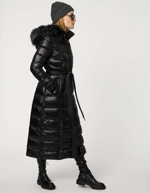 Person wearing a long black puffer coat with a fur-lined hood on a white background