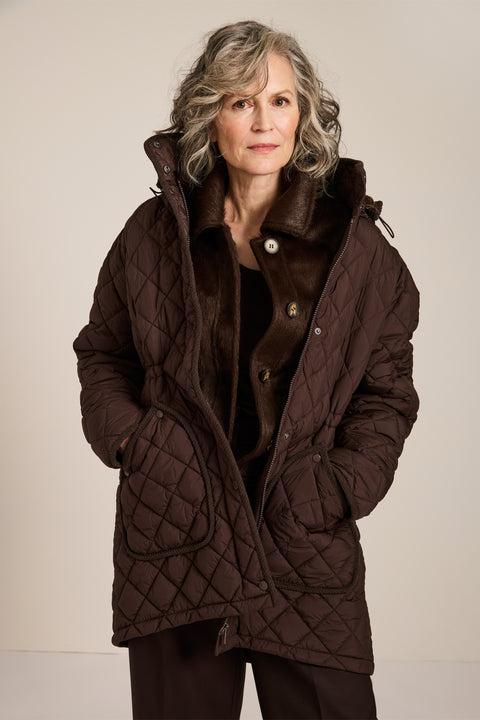 quilted hip length puffer jacket with a zip up enclosure and button up zip cover for women