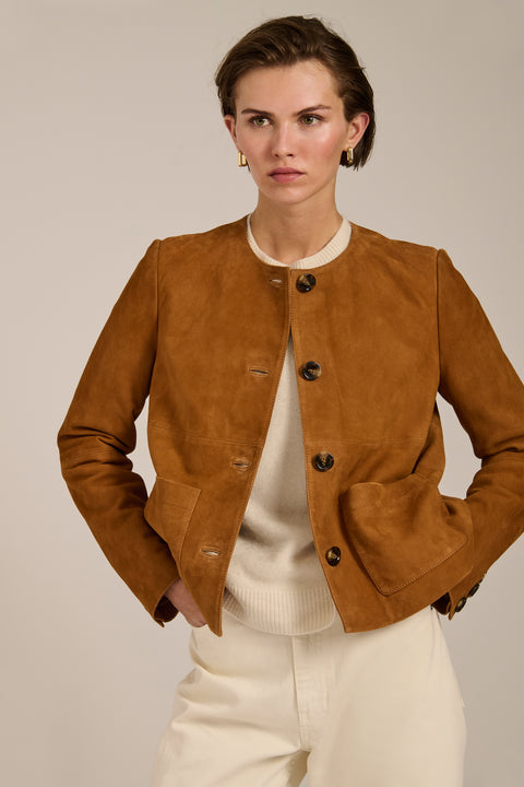 Collarless genuine suede jacket with oversized patch pockets, button-front closure and tailored silhouette.