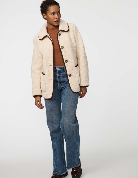 Plush sherpa coat with contrast trim, tortoise shell buttons, and patch pockets for cozy styling.
