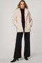Woman wearing a cream sherpa coat on a white background