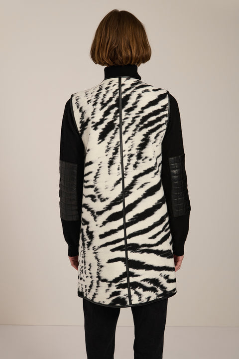 Long Bengal-inspired faux fur vest with collarless silhouette, faux leather trim and elongated fit.