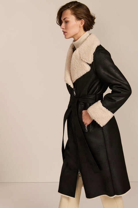 women's black faux shearling belted coat featuring ivory contrast trim, oversized notched collar, zip-front closure and zip pockets.