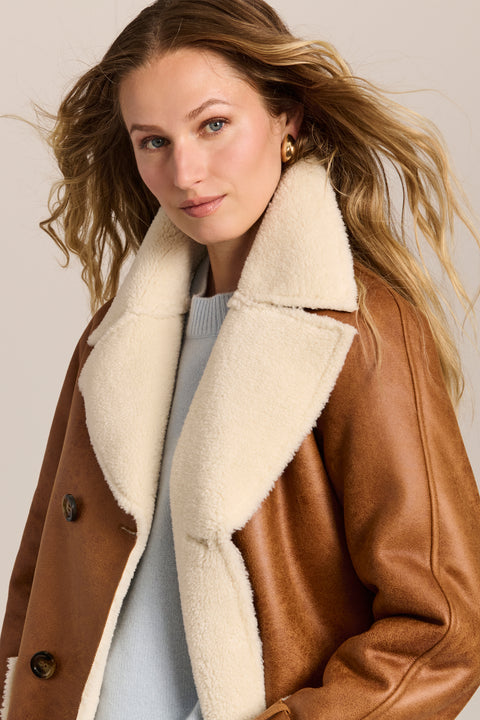 women's faux shearling coat featuring ivory contrast trim, an oversized notched collar, double-breasted button closure and patch pockets.