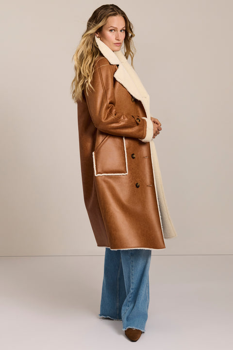 women's faux shearling coat featuring ivory contrast trim, an oversized notched collar, double-breasted button closure and patch pockets.