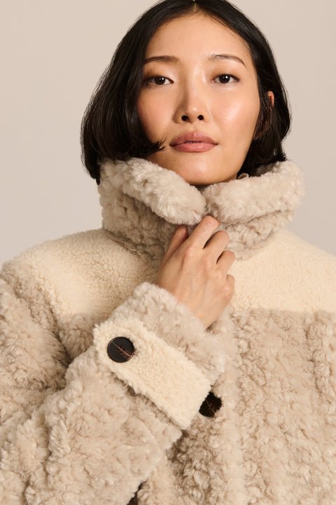 women's cream mixed-media teddy jacket with contrasting faux shearling textures, oversized patch pockets, button-front closure, and a plush stand collar.