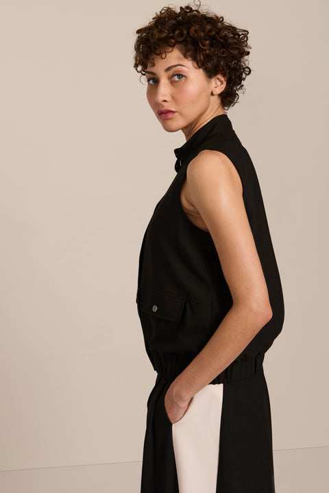 women's black sleeveless utility bomber vest featuring a stand collar, snap-front closure, flap pockets and elasticized hem.