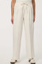 Woman wearing cream white pleated drawstring trousers with elastic waist and straight-leg silhouette.