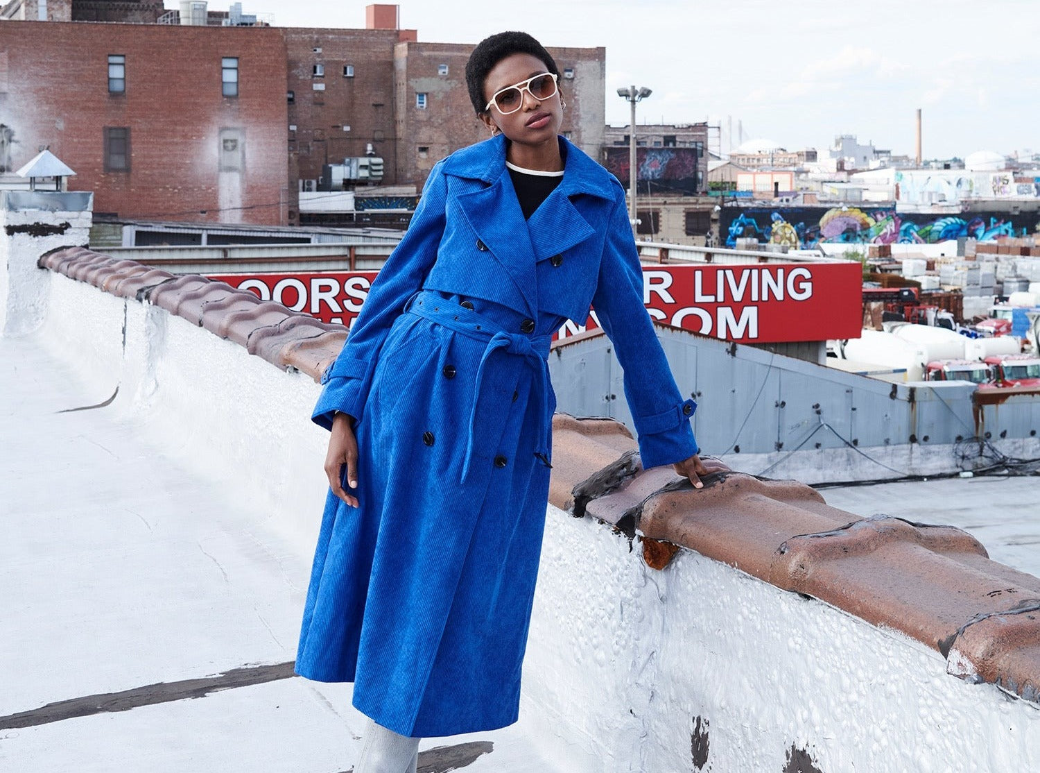 A stylish woman posing in a blue sustainable overcoat.