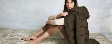 A woman in a long puffer coat sitting down.