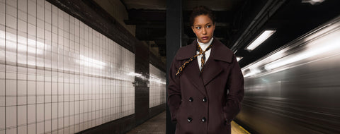 A woman in a wool coat inside a train station.