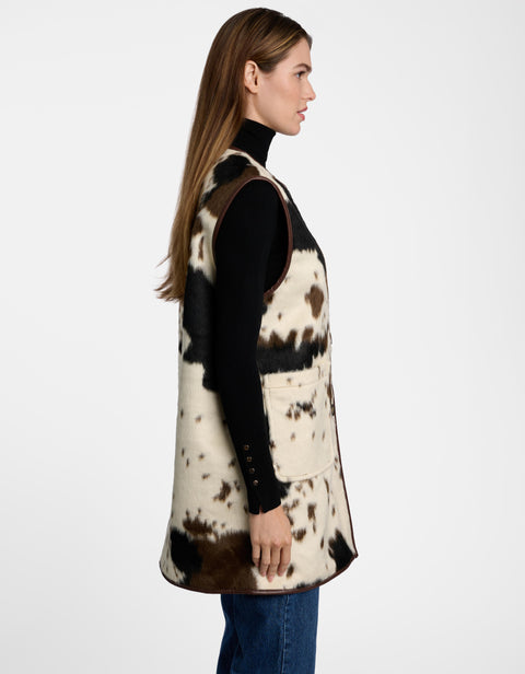 A lady in profile wearing a long Dakota Cow Print Vest and jeans.