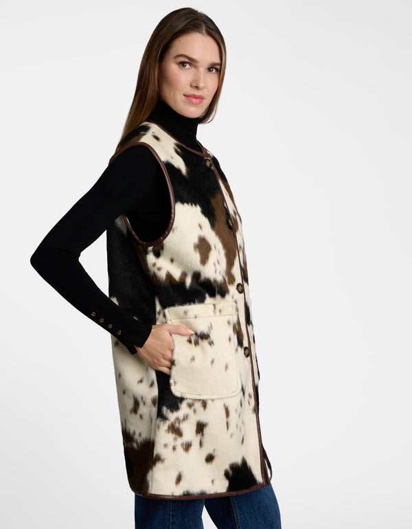 Patch pockets and button closures on a cow print sleeveless vest.
