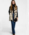 A model in a faux fur cow print vest for women with patch pockets and button closures.
