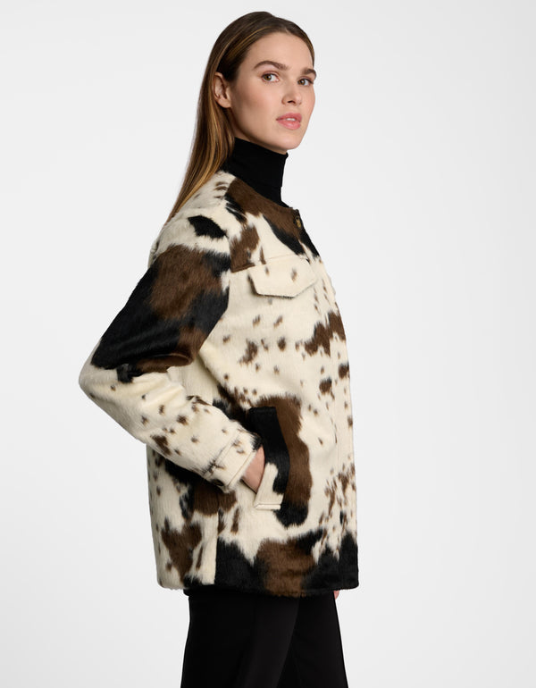 Woman wearing a cow print utility jacket on a white background.