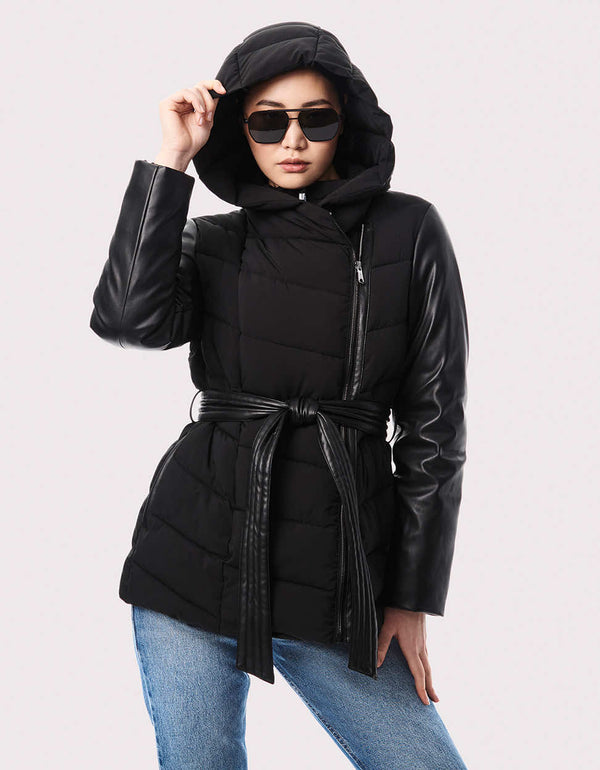 A women's belted puffer jacket with vegan leather sleeves, asymmetrical zipper, and zip-off hood for versatile styling.