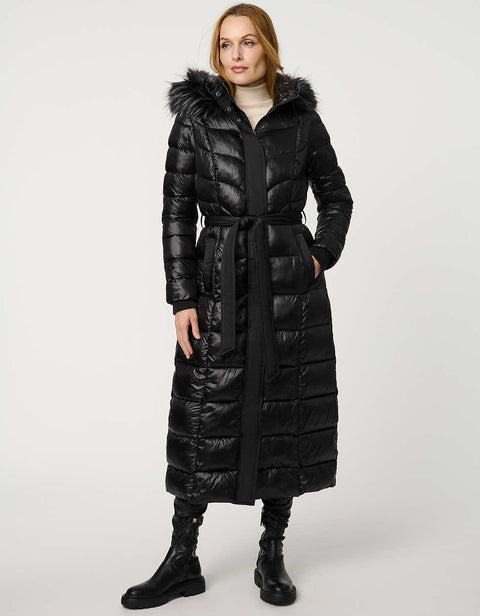 Woman wearing a long black puffer coat with a fur-lined hood on a white background
