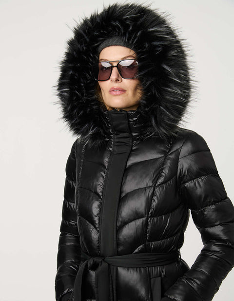 Person wearing a black puffer jacket with a fur-lined hood on a light gray background