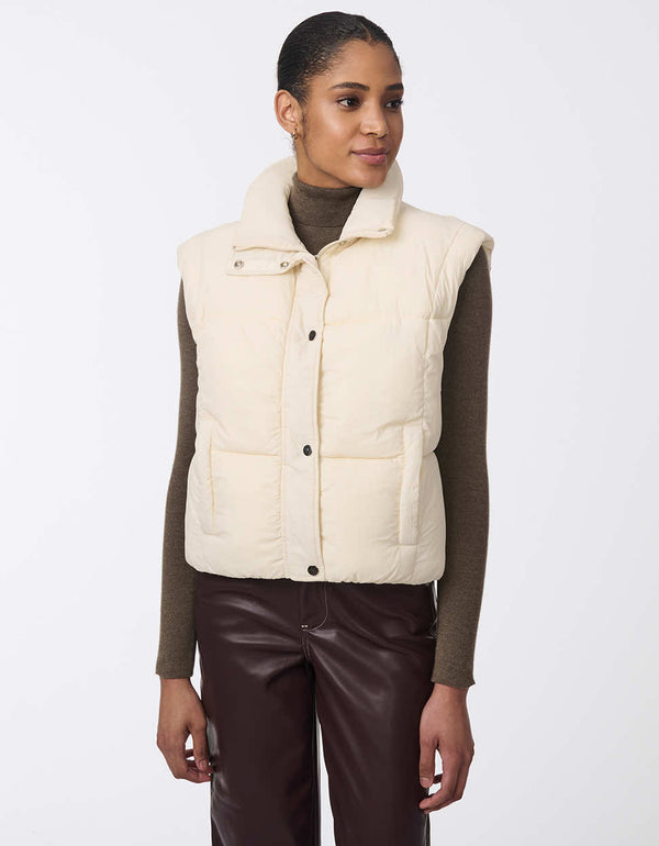 Women's sustainable puffer vest made with recycled materials. Hip-length with zipper and snap closure