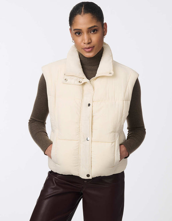 Women's sustainable puffer vest made with recycled materials. Hip-length with zipper and snap closure