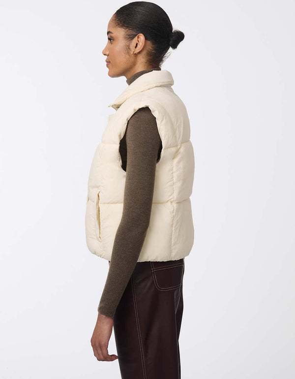 Women's sustainable puffer vest made with recycled materials. Hip-length with zipper and snap closure