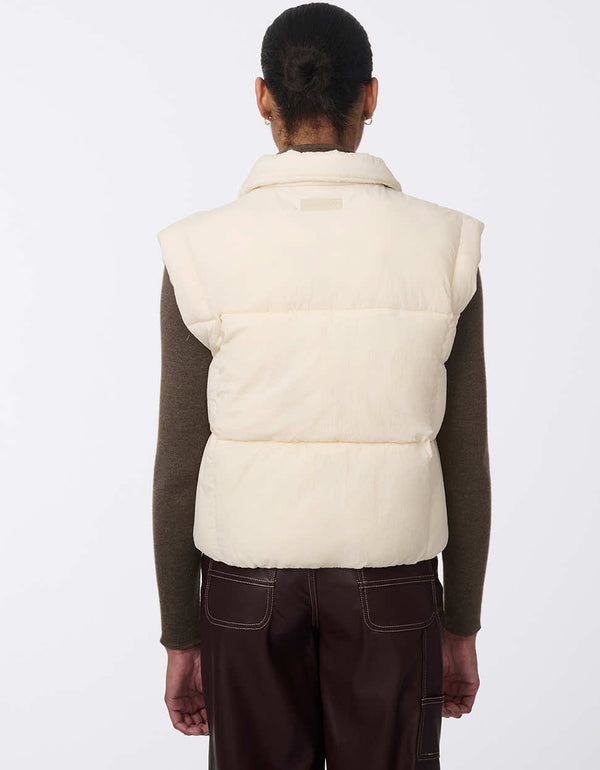 Women's sustainable puffer vest made with recycled materials. Hip-length with zipper and snap closure