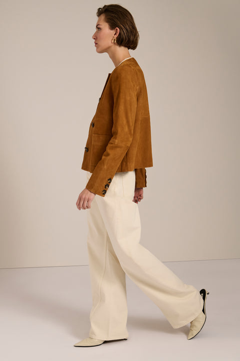 Collarless genuine suede jacket with oversized patch pockets, button-front closure and tailored silhouette.