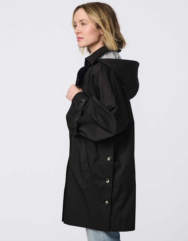 Oversized double-breasted trench with adjustable cuff straps, drawstring hood, and side button accents. Effortless, sophisticated layering piece.