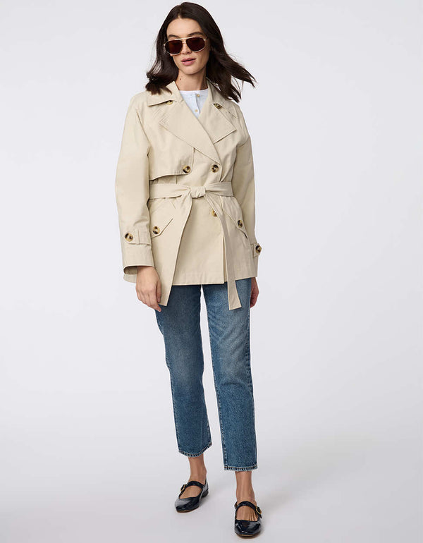 Women's cropped trench coat in a bone color, featuring a double-breasted front and  belted waist. A modern take on the timeless trench, perfect for layering in transitional weather.