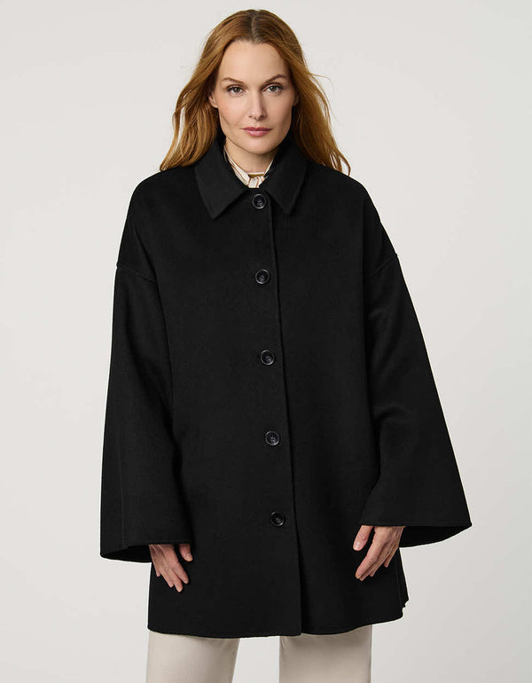 Modern women’s wool poncho coat with draped silhouette, side slits, structured collar, and welt pockets.
