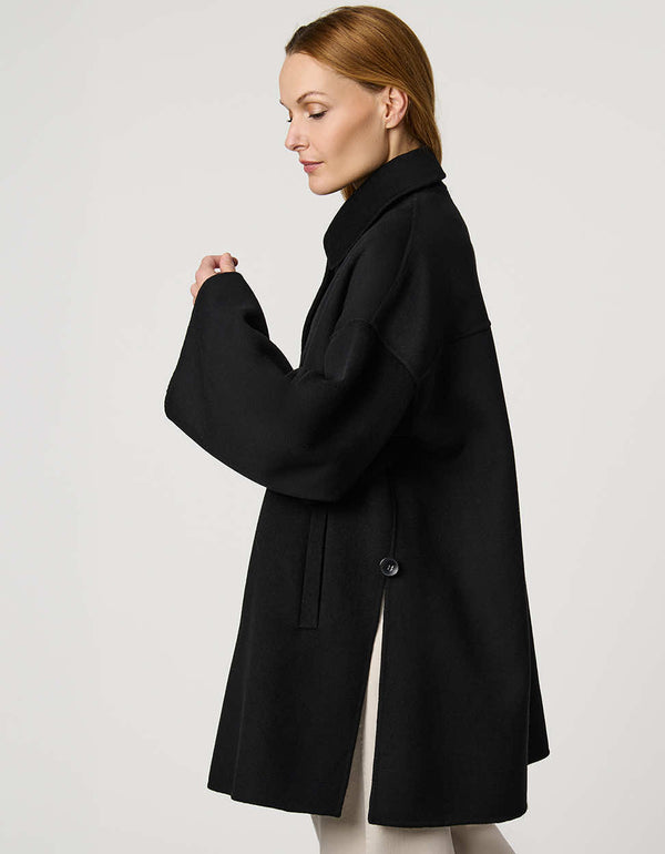 Modern women’s wool poncho coat with draped silhouette, side slits, structured collar, and welt pockets.