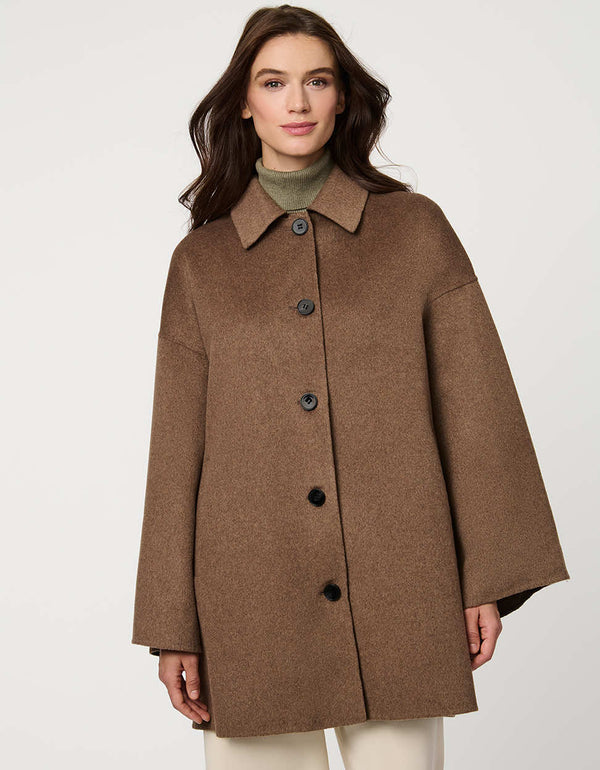 Modern women’s wool poncho coat with draped silhouette, side slits, structured collar, and welt pockets.