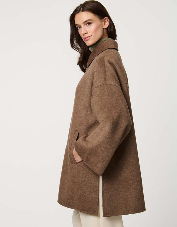 Modern women’s wool poncho coat with draped silhouette, side slits, structured collar, and welt pockets.