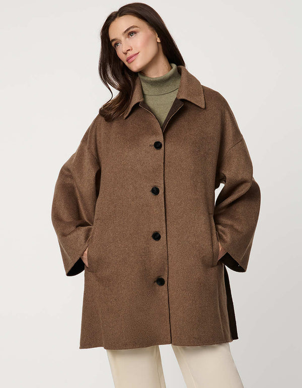Modern women’s wool poncho coat with draped silhouette, side slits, structured collar, and welt pockets.