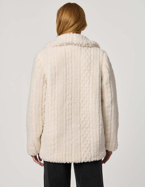 Person wearing a cream-colored textured coat on a plain background