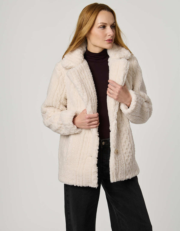Woman wearing a cream sherpa jacket against a white background