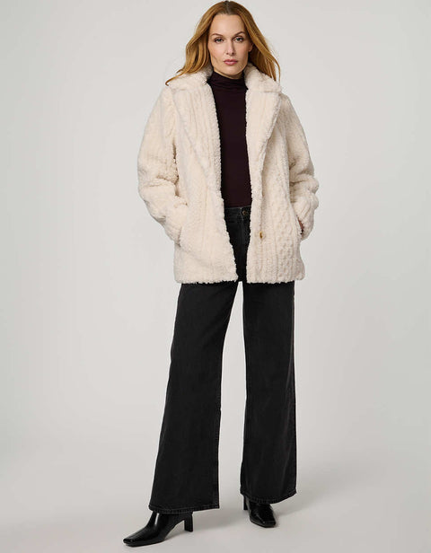 Woman wearing a cream sherpa coat on a white background