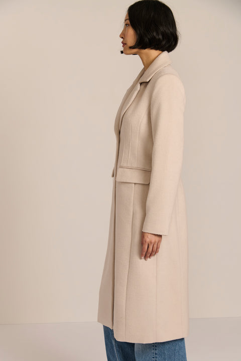 Women’s knee-length wool coat with tailored darts, patch pockets, and single-breasted three-button front.