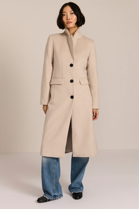 Women’s knee-length wool coat with tailored darts, patch pockets, and single-breasted three-button front.