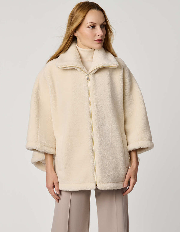 Oversized women’s sherpa poncho coat with zip-up collar, pull tabs, welt pockets, and oversized collar.