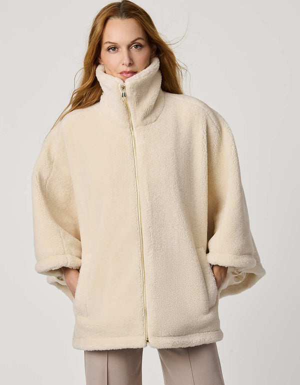 Oversized women’s sherpa poncho coat with zip-up collar, pull tabs, welt pockets, and oversized collar.