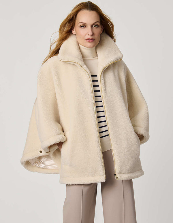 Oversized women’s sherpa poncho coat with zip-up collar, pull tabs, welt pockets, and oversized collar.