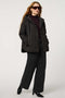 Oversized quilted puffer jacket with diamond stitching, drawstring hood, welt pockets, and snap front closures.