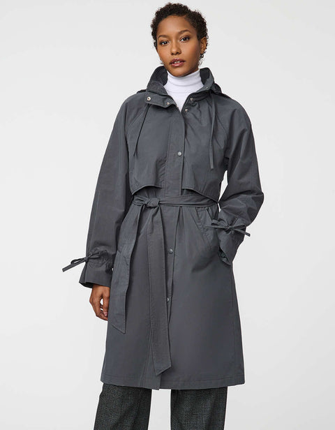 Calf-length women’s trench coat with belt, adjustable cuffs, and packable hood, ideal for transitional weather.