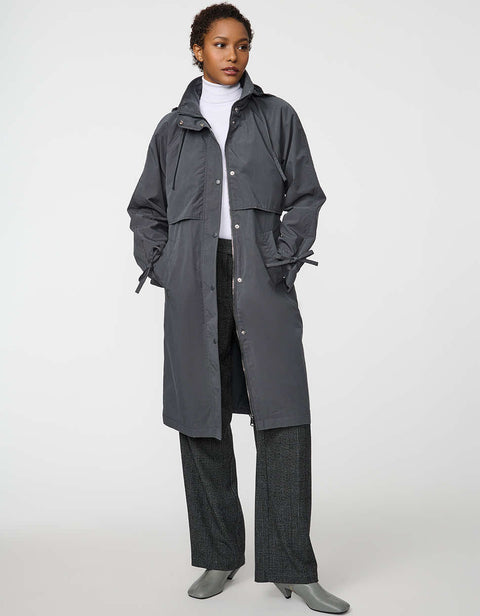 Calf-length women’s trench coat with belt, adjustable cuffs, and packable hood, ideal for transitional weather.