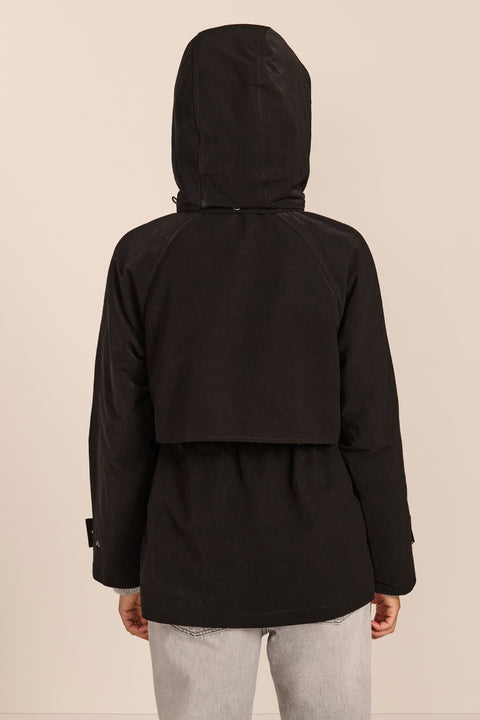 Women's hooded raincoat with drawstring waist, storm flap, side pockets and adjustable cuffs.