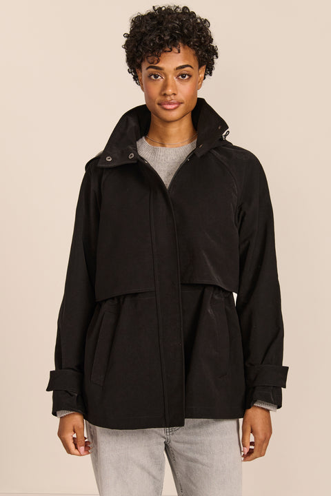 Women's hooded raincoat with drawstring waist, storm flap, side pockets and adjustable cuffs.