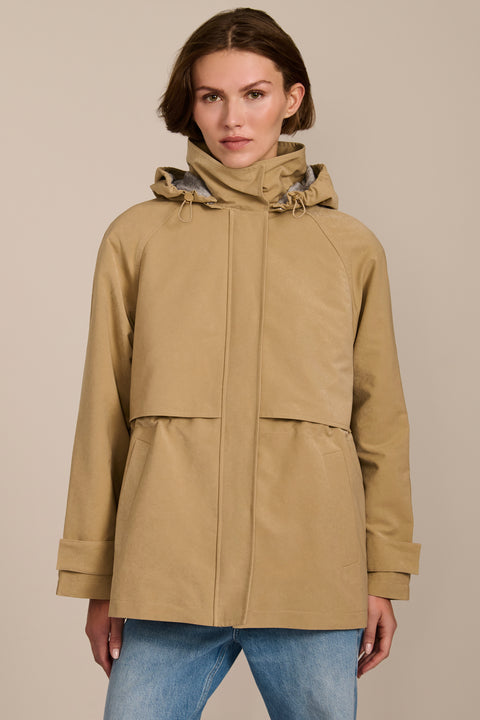 Women's hooded raincoat with drawstring waist, storm flap, side pockets and adjustable cuffs.