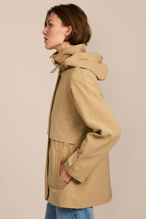 Women's hooded raincoat with drawstring waist, storm flap, side pockets and adjustable cuffs.